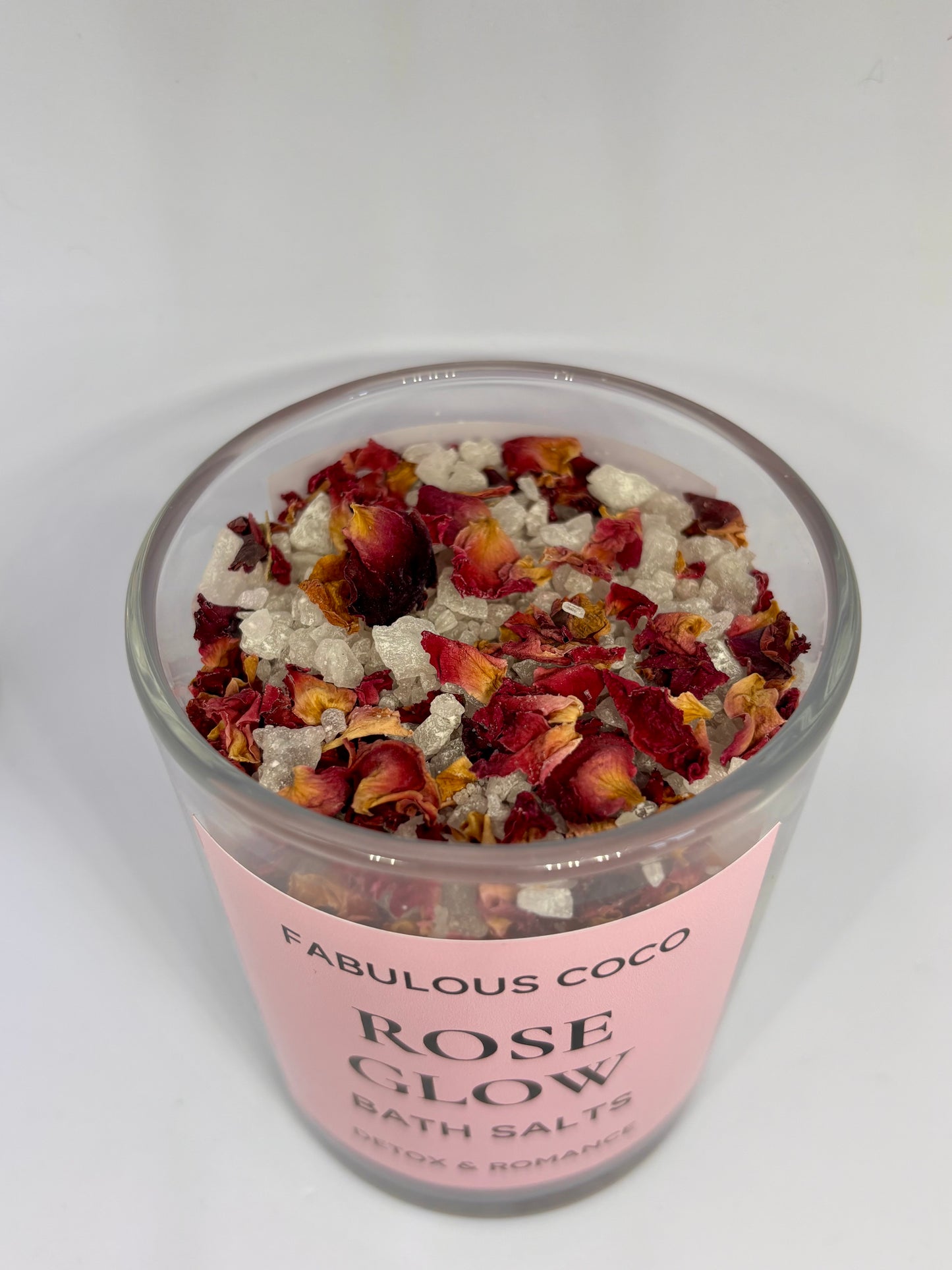 Rose Glow Bath Salts in a clear jar with bamboo lid and pink label.